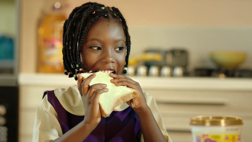 image of a little black girl eating Mamador butter and bread. Healthy Breakfast